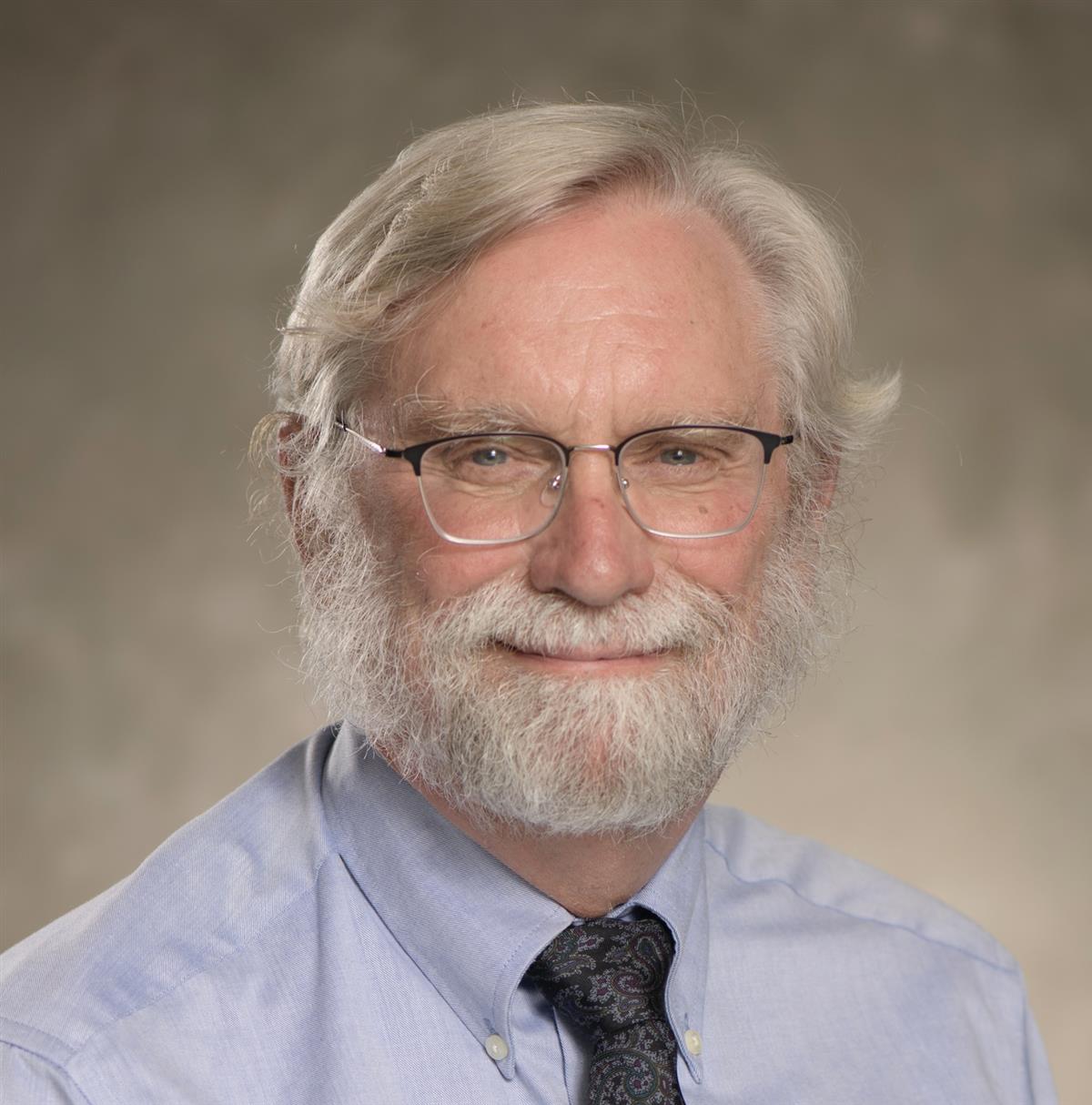 A glasses wearing older white man with pale blonde/white hair and beard.